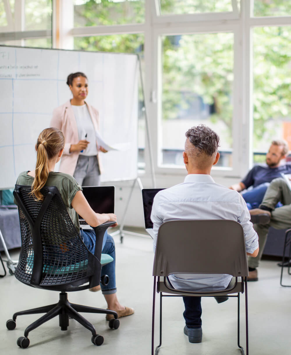 A professor at a whiteboard teaching a small group of seated students